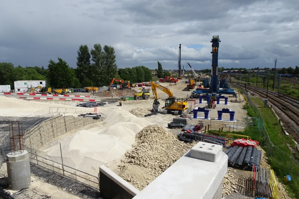 Obra de infraestrutura viária com terraplenagem, máquinas e materiais em etapas diferentes de execução